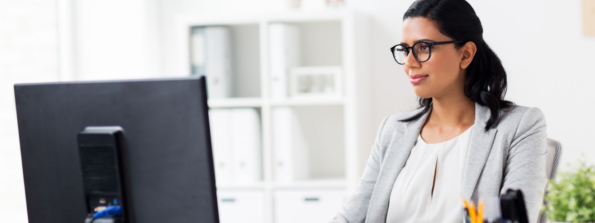 Black woman engineer with crossed arms standing in a server room, smiling confidently.